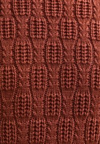 Gebreid textiel in een diepe rode kleur, met een gestructureerd patroon van ovale vormen met open weefsel en dicht gebreide secties.