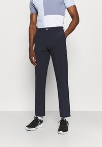 Dark navy pants with a slim fit design, made from a smooth fabric. Paired with a color-blocked light blue and white short sleeve top.