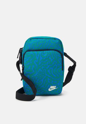 Torba na ramię Nike z niebiesko-zielonym wzorem fal, wykonana z materiału tkanego, z zamkiem błyskawicznym oraz regulowanym czarnym paskiem z detalem logo.