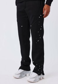 Zwarte joggingsbroek met een textuurafwerking, voorzien van witte accentpunten en zilverkleurige hardware op de zakken, ontworpen voor een aansluitende fit.