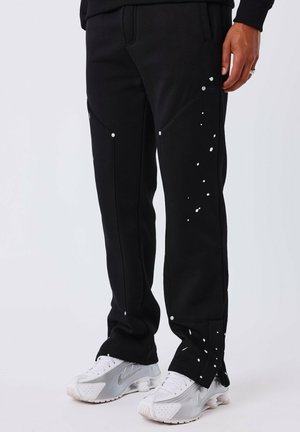 Zwarte joggingsbroek met een textuurafwerking, voorzien van witte accentpunten en zilverkleurige hardware op de zakken, ontworpen voor een aansluitende fit.
