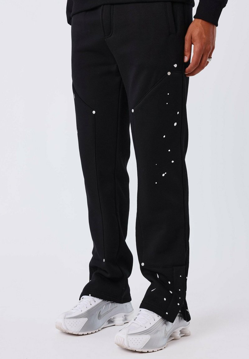 Zwarte joggingsbroek met een textuurafwerking, voorzien van witte accentpunten en zilverkleurige hardware op de zakken, ontworpen voor een aansluitende fit.