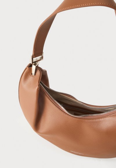 Sac à main en cuir marron avec une large bandoulière cousue et une fermeture éclair argentée partiellement ouverte montrant la doublure intérieure.