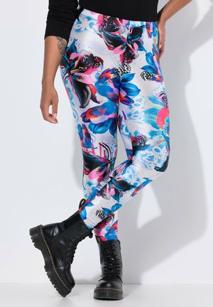 Leggings med stort, farverigt blåt, lyserødt og sort blomsterprint, båret med sorte støvler og en sort bluse med lange ærmer.