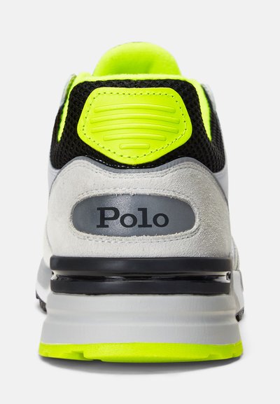 Grå mockasinsneaker med svart mesh, neon gula detaljer, platt svart logopatch, vadderad krage och en svart sula med en synlig luftkassett.