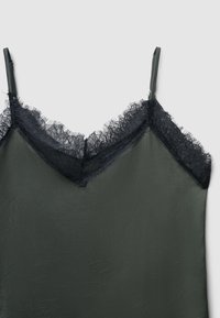 Top in verde olivo con pizzo nero lungo il scollo e le spalline, caratterizzato da un tessuto texturizzato e un design a forma di V.