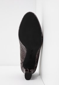 Vue unique d'une botte cheville à bout pointu, effet peau de serpent marron avec une semelle en caoutchouc noire et un talon bloc, sur fond blanc.
