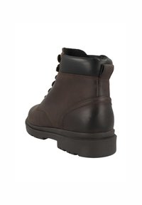 Bottine en cuir marron avec un bout arrondi, accents en caoutchouc noir, six oeillets et une semelle texturée pour une meilleure adhérence.