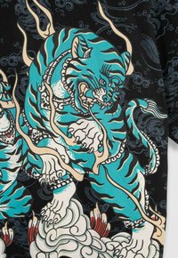 Niebiesko-czarny stylizowany tygrys z kremowymi płomieniami i misternymi wzorami, stojący na wirujących białych chmurach na ciemnym tle.