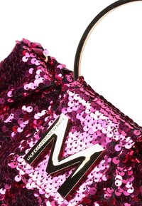 Bolso de mano de lentejuelas rosas con una correa metálica y un logo grabado "M". La textura es brillante y reflectante con lentejuelas densamente compactadas.