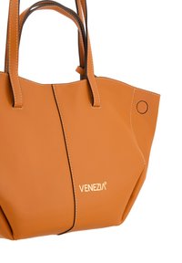 Sac fourre-tout en cuir orange avec des coutures blanches contrastantes, doté de deux poignées et d'un accent rond. Logo VENEZIA affiché sur le devant.
