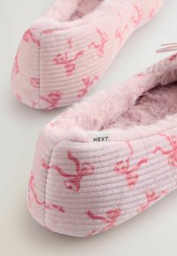 Roze pluche pantoffels met ribbeltextuur, voorzien van een zachte faux bont voering en een subtiel roze patroon. Inclusief een "NEXT" label.