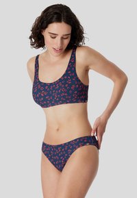 Námořnický bikini set s červeným květinovým vzorem. Podprsenka má široké ramínka a zaoblený výstřih; kalhotky jsou nízko střihané a mají elastický pas pro pohodlí.
