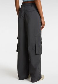 Pantaloni cargo neri caratterizzati da un design a gamba larga, due tasche laterali e lacci regolabili. Realizzati in un tessuto leggero e resistente.