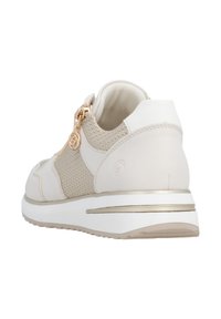 Beige athletic shoe featuring a textured knit upper, smooth leather accents, gold zipper detail, and a cushioned sole with a gold stripe.