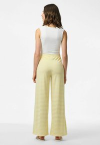 Gele gestreepte wijde broek met een elastische tailleband, gecombineerd met een witte mouwloze top. Gladde stof en relaxte pasvorm.