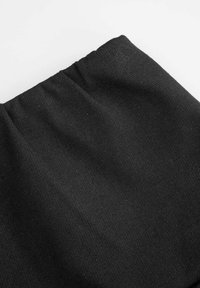 Czarna tkanina o gładkiej fakturze, z subtelnym prążkowanym wzorem. Góra zakończona marszczeniem, co wskazuje na elastyczny pas w talii.