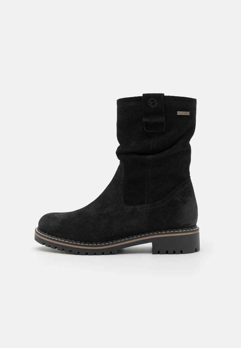 Bottine en cuir suédé noir avec un dessus replié et un détail de boucle. Semelle en caoutchouc épaisse avec une bonne adhérence, couture contrastante claire le long du bord.