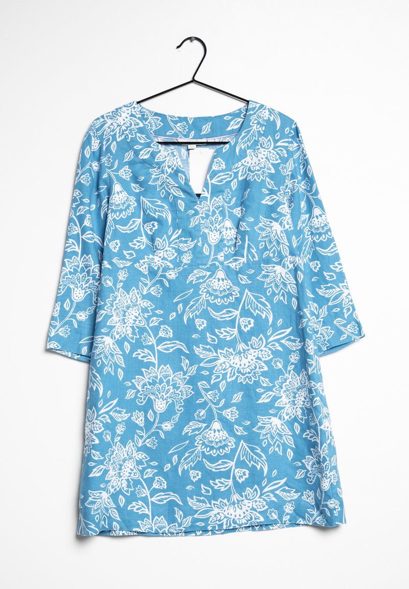 Robe bleue longueur genou avec motif floral blanc, manches trois-quarts et petit col en V devant, suspendue sur un cintre noir.