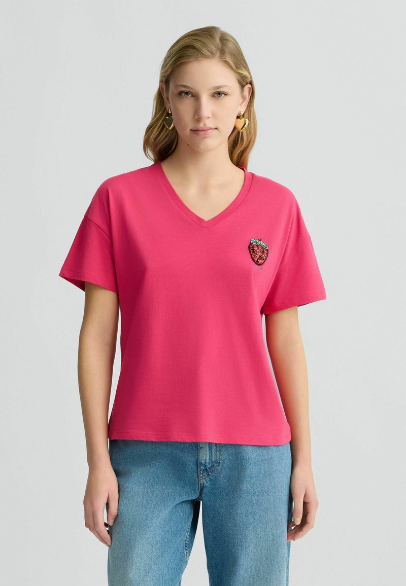 Lyserød bomulds-T-shirt med V-udskæring, korte ærmer og et broderet jordbærmotiv på venstre bryst. Casual pasform og blød tekstur.