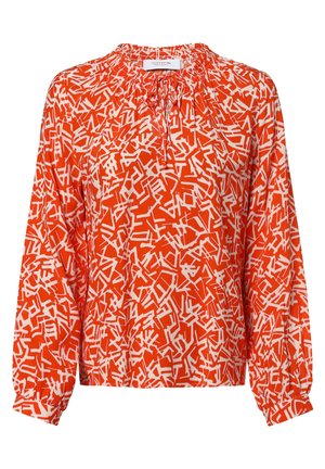 Langærmet orange bluse med hvidt abstrakt geometrisk mønster, rynket halsudskæring med bindebånd og elastiske manchetter.