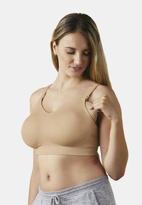 Nagi rozciągliwy biustonosz z regulowanymi ramiączkami, gładką powierzchnią i bezszwowym designem, w połączeniu z szarymi spodniami dresowymi dla komfortu.