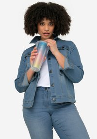 Veste en denim bleu clair avec un col, des boutons sur le devant et deux poches sur la poitrine. Tient un gobelet en plastique de couleur dégradée avec une surface texturée.