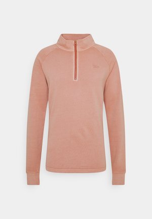 Langärmeliger, hellrosa Pullover mit Stehkragen und kurzem Frontreißverschluss, dargestellt vor einem schlichten grauen Hintergrund.