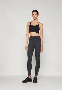 Fekete sportos crop top és magas derekú leggings, rugalmas anyagból, sima textúrával és testhezálló fazonnal.