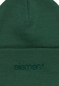 Beanie verde lavorato a maglia in tessuto morbido, con un logo in rilievo sottile. Il design ha una forma aderente con una parte superiore senza cuciture.
