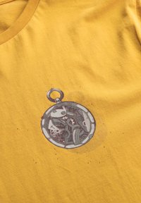 T-shirt di cotone gialla con un design di un orologio da tasca stampato in grigio e nero, con dettagli intricati visibili all'interno del quadrante dell'orologio.
