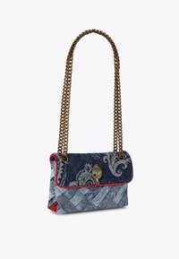 Borsa in denim con design intrecciato, tonalità blu e grigio, rifiniture rosse, tracolla in catena color oro e chiusura decorativa.