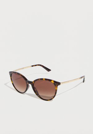 Runde Schildpatt-Sonnenbrille mit braunen Verlaufsgläsern und schlanken goldenen Metallbügeln auf weißem Hintergrund.