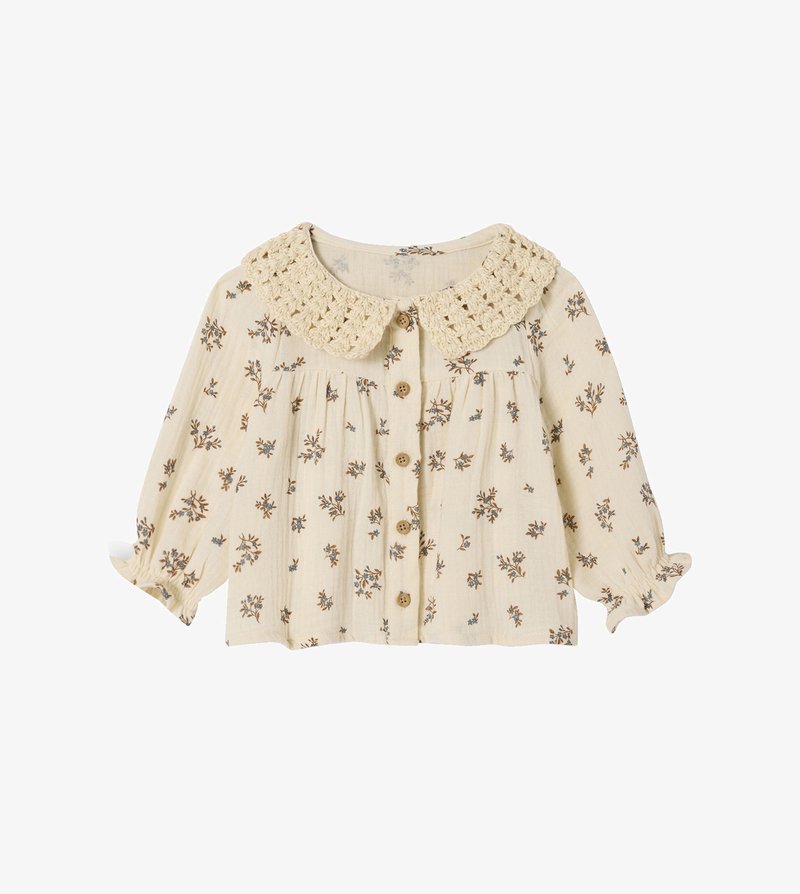 Cream blouse with floral print in blue and brown, featuring a crochet collar, button closure, and gathered sleeves. Lightweight, textured fabric.