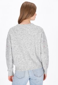 Pulover gri tricotat cu guler rotund, prezentând mărgele decorative colorate de-a lungul mânecilor. Croială lejeră, cu tiv și manșete curbate.