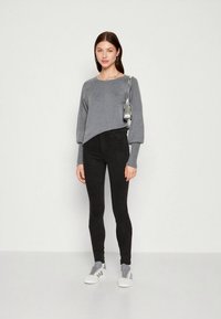 Suéter cinza cropped com mangas compridas, combinado com jeans skinny pretos e ténis cinza. Corte slim e textura suave com detalhes mínimos.