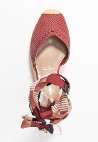 Rote gewebte Espadrilles mit offener Zehe und Jute-Plattform. Befestigter gemusterter Stoff in Rottönen, Weiß und Marineblau, der am Knöchel gebunden ist.