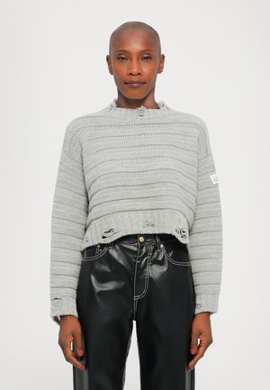 Gray knitted sweater with horizontal stripes, cropped fit, tattered hem, and crew neckline. Paired with black leather pants and contrast stitching.
