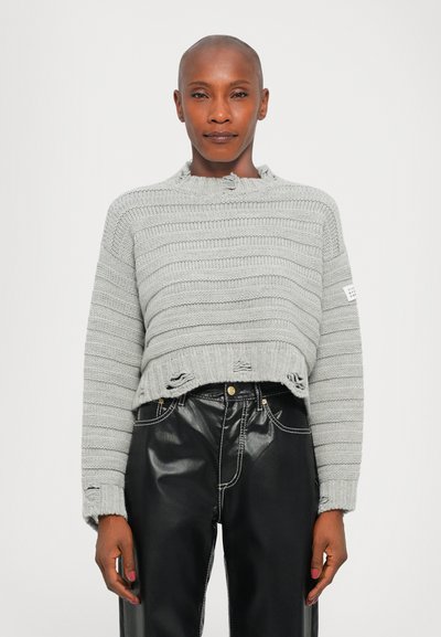 Maglione grigio lavorato a maglia con righe orizzontali, taglio corto, orlo sfilacciato e collo a giro. Abbinato a pantaloni in pelle neri con cuciture a contrasto.