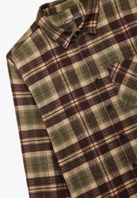 Gekleurde flanellen shirt in groen, bruin en beige met blauwe accenten. Bevat een kraag, knoopsluiting aan de voorkant en een enkele borstzak. Zachte textuur.