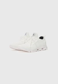 Zapatillas deportivas blancas con parte superior de malla, punta redondeada y detalles texturizados, que cuentan con una suela acolchada con bolsillos de aire visibles.