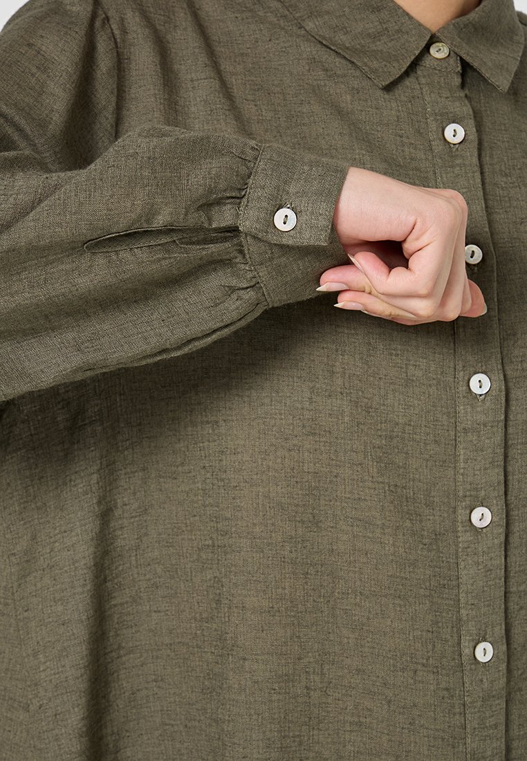 Chemise vert olive en tissu texturé avec un devant boutonné et un col classique. Dispose de manches à bouton et d'une coupe décontractée.