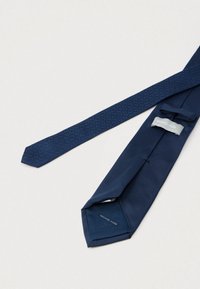 Granatowy krawat z gładkiej tkaniny, z fakturowanym wzorem na wąskim końcu. Przymocowana metka z napisem "Michael Kors".