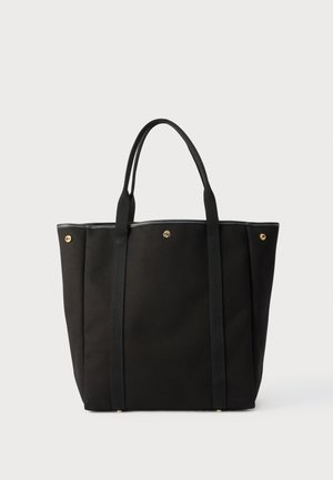 Czarna torba na ramię z podwójnymi paskami na ramiona, złotymi zatrzaskami na górnych krawędziach i minimalistycznym wzorem na neutralnym tle.