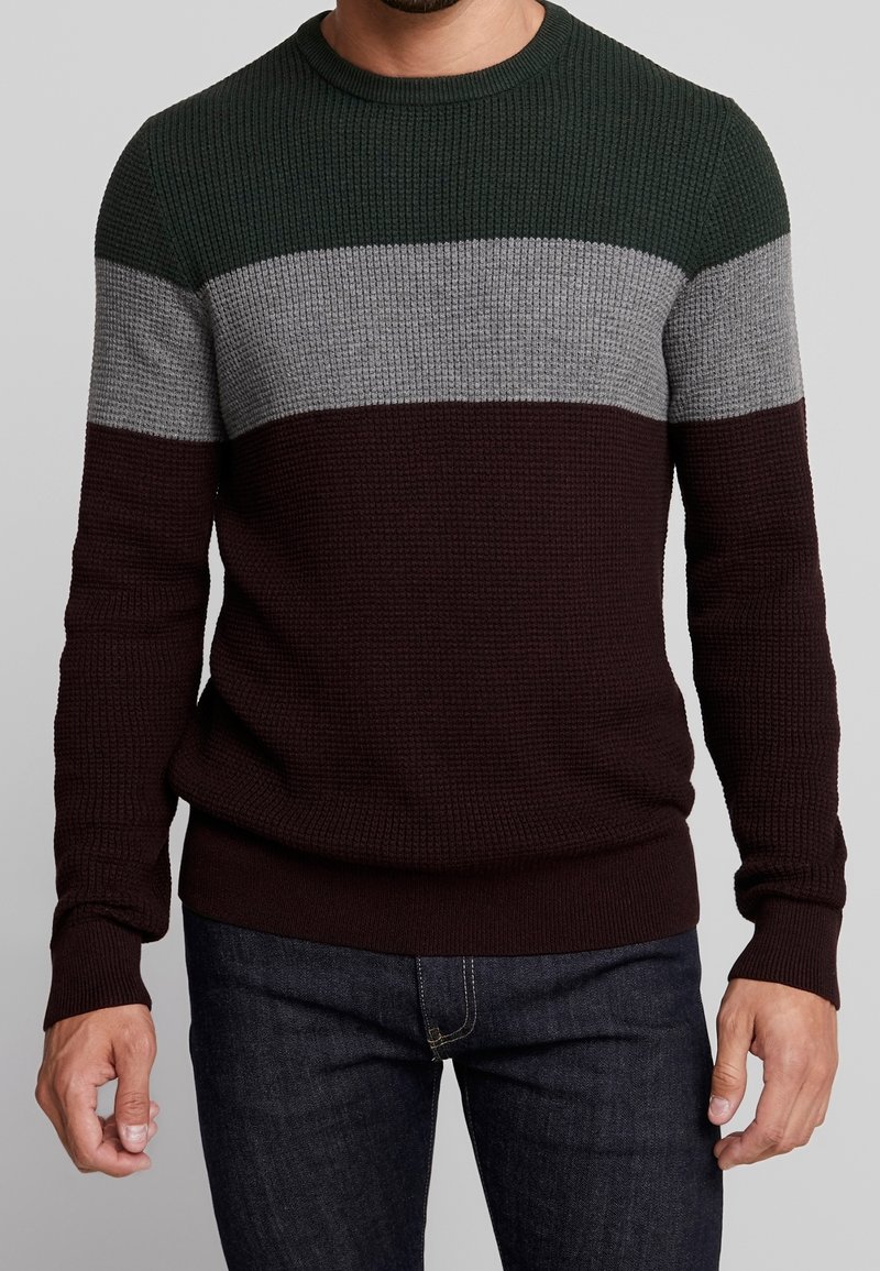 Gestrickter Pullover mit horizontalen Streifen in Dunkelgrün, Grau und Burgund. Rundhalsausschnitt, gerippte Bündchen und Saum. Waffelstruktur über das gesamte Kleidungsstück.