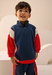 Blå og rød lynlås sweatshirt med høj krave og farveblokdesign. Lavet af blødt stof, med ribbede manchetter og kant.