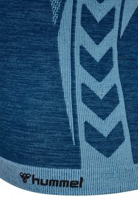 Blaues sportliches Top mit strukturierter Stoffqualität, versehen mit einem hellblauen Chevron-Muster und einem schwarzen "hummel"-Logo am Saum.