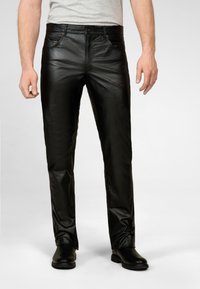 Zwarte leren broek met een slimfit ontwerp, voorzien van voorzakken en een gladde textuur. De broek is gecombineerd met zwarte schoenen.