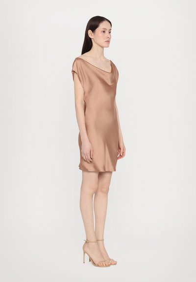Satin kjole i en varm beige farve med en rundet halsudskæring og korte ærmer. Modellen bærer beige stropheel, stående imod en hvid baggrund.