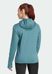 Teal atletisk hoodie med en snodd huva, texturerat tyg och långa ärmar. Har subtila logodetaljer på vänster axel.